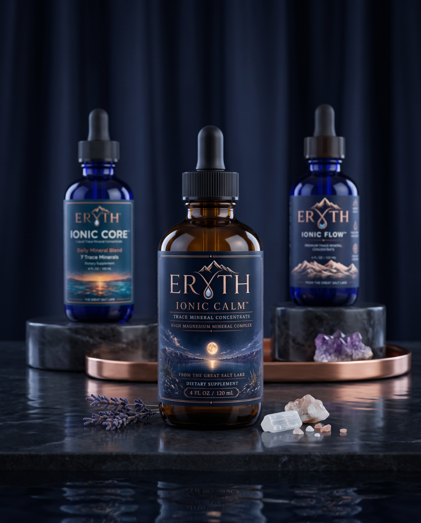 ERYTH liquid trace mineral formula lineup — Ionic Flow, Ionic Core, and Ionic Calm cobalt blue dropper bottles on a travertine stone slab.